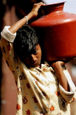 A boy carries water to his family