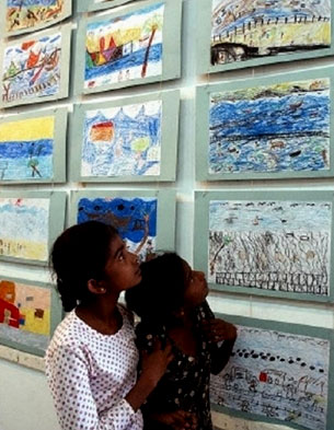 Two young girls view other children's drawings of the tsunami in Sri Lanka