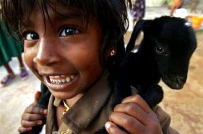 A young girl carries her baby goat on her back