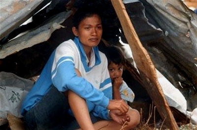 A woman and her son rest in their makeshift shelter