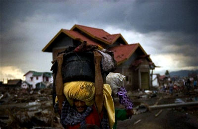 A man carries some of his personal items from his destroyed home in Banda Aceh, Indonesia