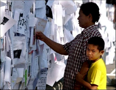 A father and his child view missing people notices