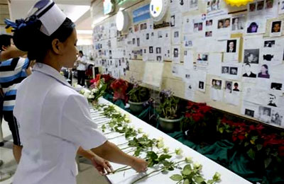 A nurse places a rose in front of missing people notices