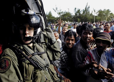 Villagers crowd around a U.S. Navy helicopter to receive aid