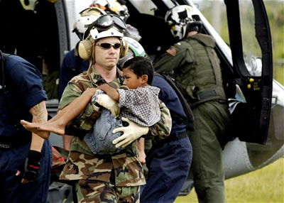 A U.S. Navy man carries a wounded child from a transport helicopter