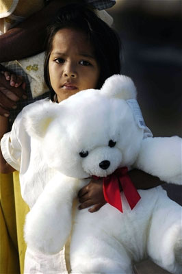 A young girl holds a teddy bear that a U.S. Navy man gave her