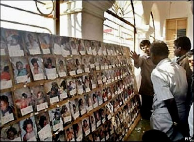 Relatives of missing people look at one of the numerous photo walls which show pictires of the dead