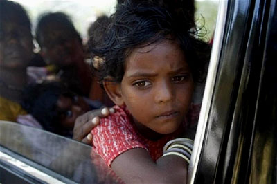 A sad young girl looks out a car window at the destruction in south India